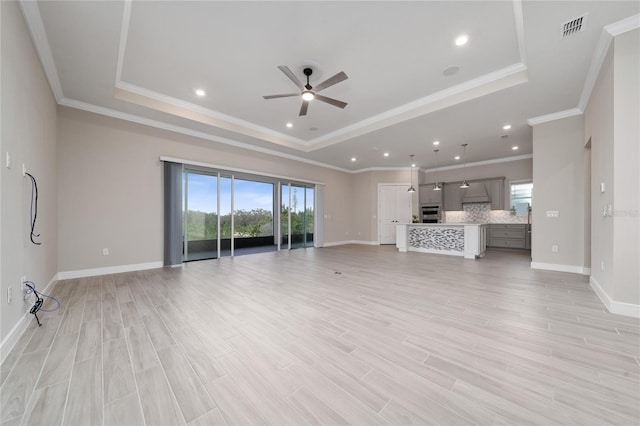 unfurnished living room with light wood-type flooring, a raised ceiling, visible vents, and baseboards