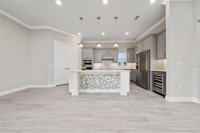 kitchen with a center island with sink, wine cooler, stainless steel appliances, light countertops, and pendant lighting