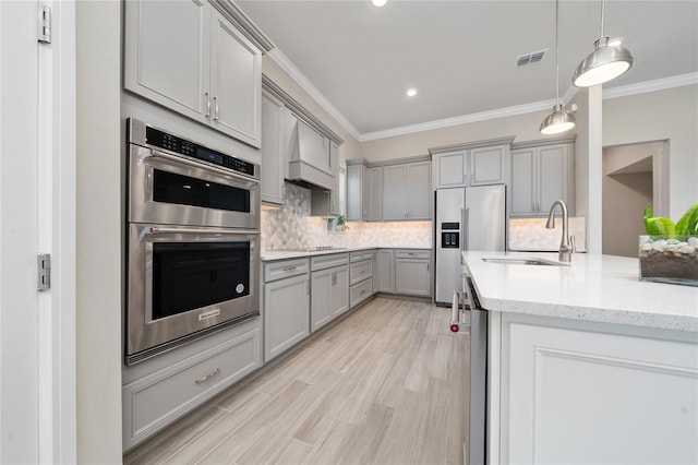 kitchen featuring gray cabinets, visible vents, appliances with stainless steel finishes, ornamental molding, and a sink