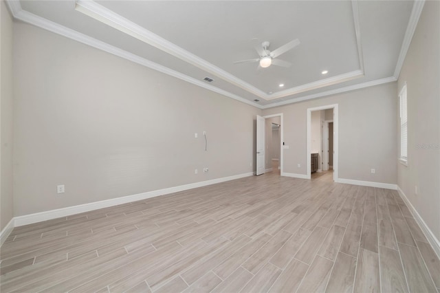 unfurnished room with ceiling fan, baseboards, light wood finished floors, a raised ceiling, and crown molding