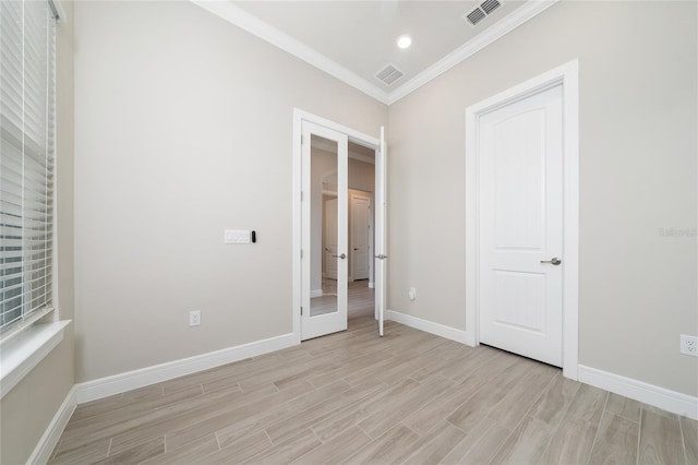 unfurnished bedroom featuring light wood-style floors, baseboards, visible vents, and crown molding