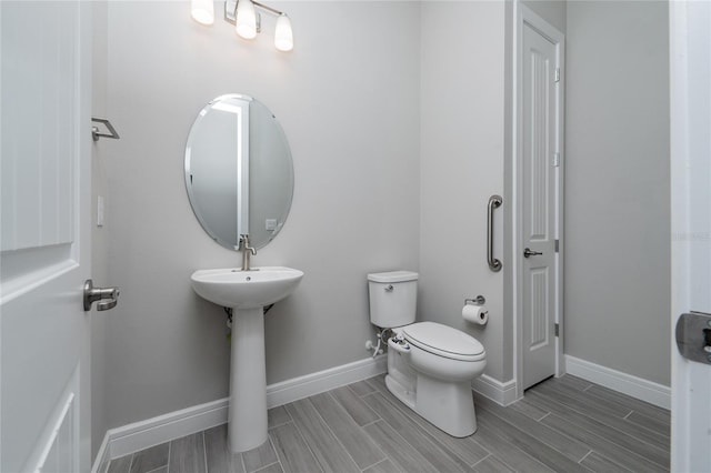 half bathroom featuring toilet, wood tiled floor, and baseboards