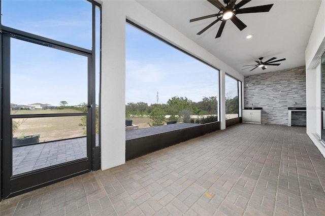 unfurnished sunroom featuring a ceiling fan