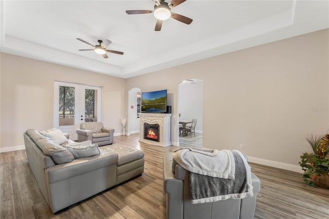 living room with french doors, wood-type flooring, ceiling fan, and a tray ceiling