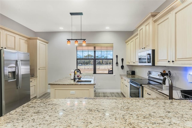 kitchen featuring sink, hanging light fixtures, stainless steel appliances, light stone countertops, and a center island with sink