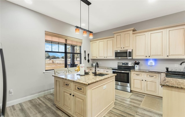 kitchen featuring stainless steel appliances, a center island with sink, sink, and pendant lighting