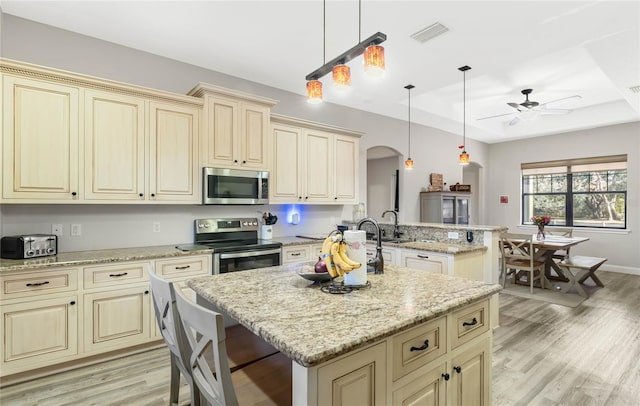 kitchen featuring a kitchen island, appliances with stainless steel finishes, pendant lighting, and a tray ceiling