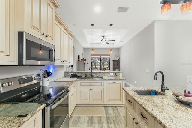 kitchen featuring light stone countertops, appliances with stainless steel finishes, sink, and decorative light fixtures