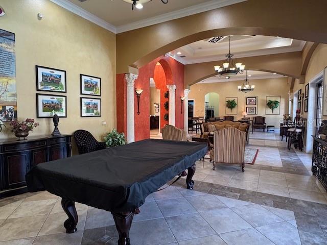 playroom with light tile patterned floors, a notable chandelier, a tray ceiling, ornamental molding, and pool table