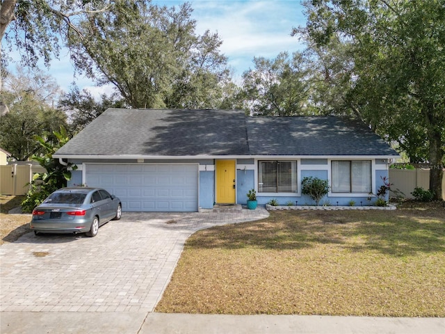 ranch-style home featuring a garage and a front lawn