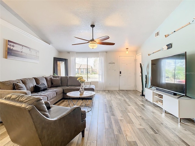 living room featuring ceiling fan, lofted ceiling, a textured ceiling, and light wood-type flooring