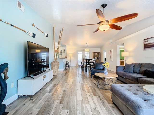 living room featuring ceiling fan, lofted ceiling, and light hardwood / wood-style floors