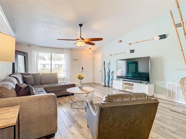 living room with vaulted ceiling, a textured ceiling, ceiling fan, and light hardwood / wood-style flooring