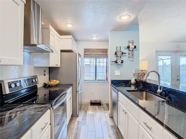 kitchen with wall chimney exhaust hood, stainless steel appliances, sink, and white cabinets