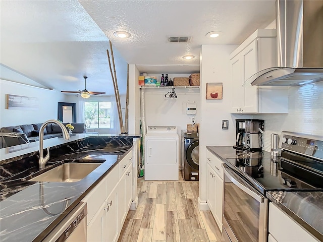 kitchen with white cabinetry, wall chimney range hood, washing machine and dryer, and appliances with stainless steel finishes