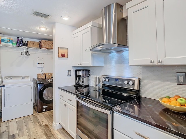 kitchen featuring white cabinets, wall chimney exhaust hood, washing machine and dryer, and electric range