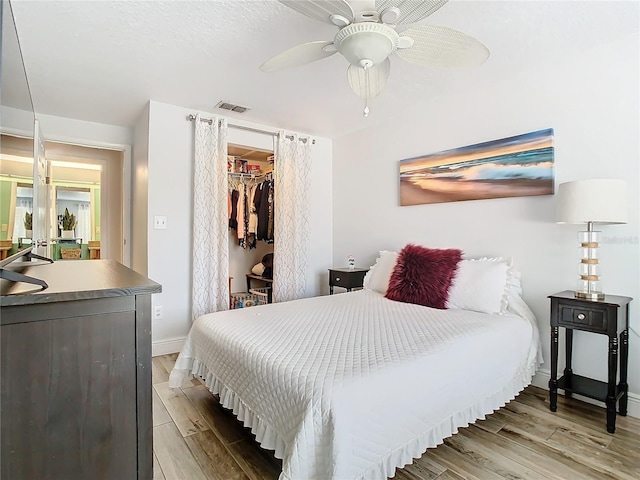 bedroom with light hardwood / wood-style flooring, a spacious closet, ceiling fan, a textured ceiling, and a closet