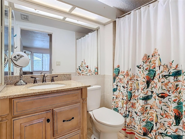 bathroom featuring vanity, toilet, and tile walls