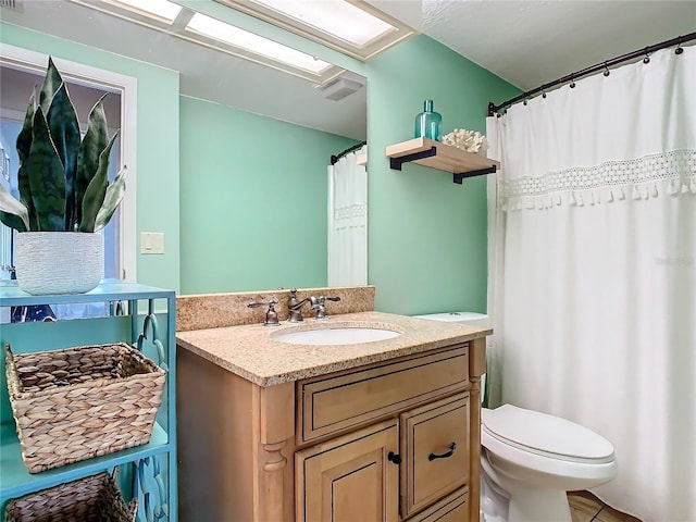 bathroom with vanity, tile patterned flooring, a skylight, and toilet