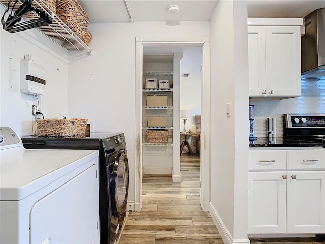 clothes washing area with washer and dryer and light hardwood / wood-style floors