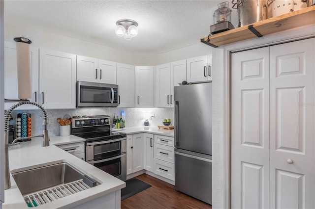 kitchen with backsplash, dark hardwood / wood-style floors, sink, white cabinetry, and appliances with stainless steel finishes