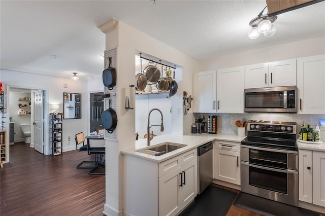 kitchen featuring dark hardwood / wood-style floors, appliances with stainless steel finishes, white cabinetry, and sink