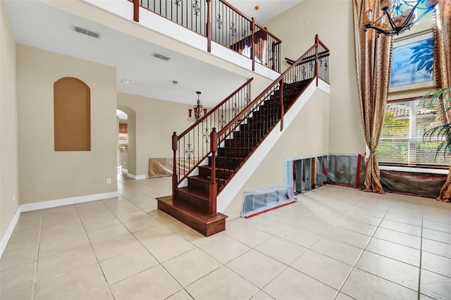 staircase featuring an inviting chandelier, tile patterned flooring, and a towering ceiling