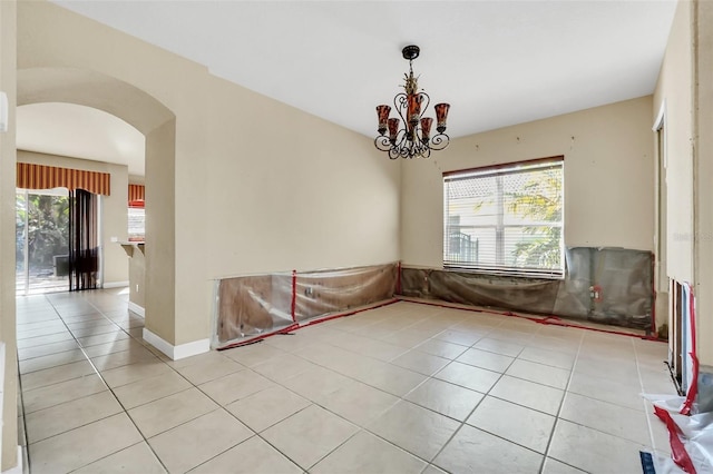 spare room featuring light tile patterned floors, plenty of natural light, and a notable chandelier