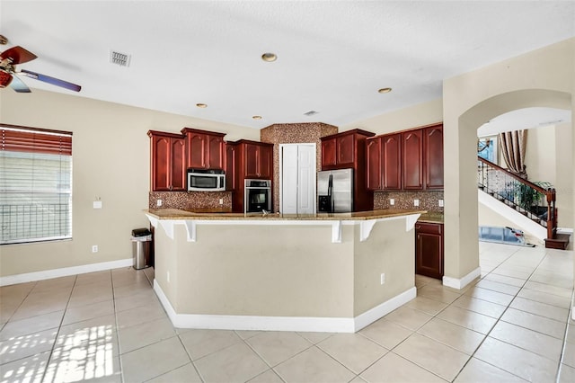 kitchen featuring stainless steel appliances, a breakfast bar area, and tasteful backsplash