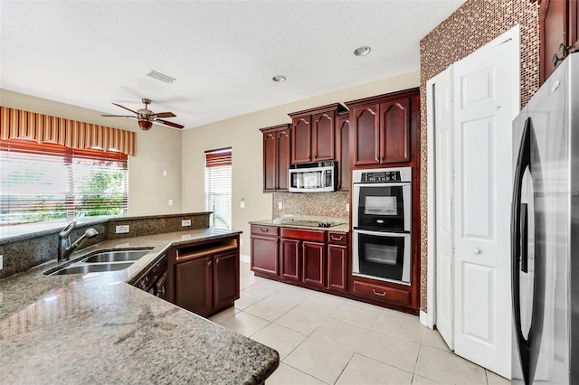 kitchen featuring light tile patterned floors, stainless steel appliances, decorative backsplash, stone countertops, and sink