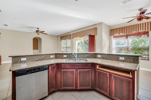 kitchen with stainless steel dishwasher, light tile patterned floors, sink, and a center island with sink