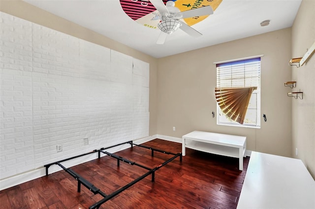 bedroom featuring ceiling fan, brick wall, and hardwood / wood-style floors