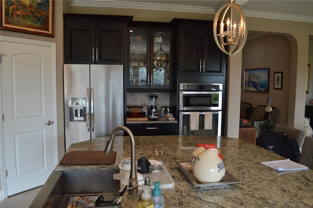 kitchen with decorative light fixtures, stainless steel appliances, ornamental molding, light stone counters, and light tile patterned floors