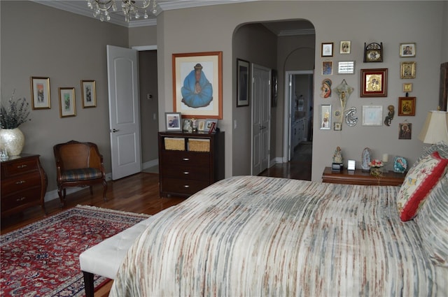 bedroom featuring a closet, dark hardwood / wood-style flooring, ornamental molding, and a notable chandelier