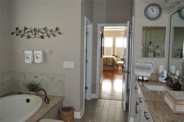 bathroom featuring tiled bath and vanity