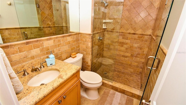 bathroom with walk in shower, vanity, tile walls, and toilet