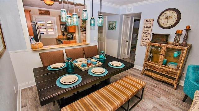 dining room with ornamental molding and light hardwood / wood-style floors