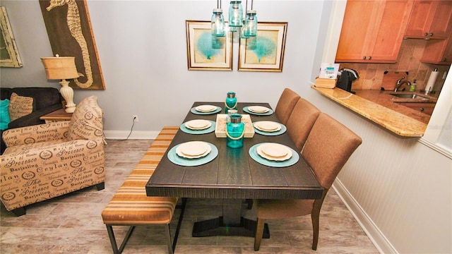 dining space with light wood-type flooring and sink