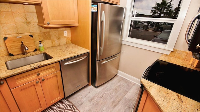 kitchen featuring light stone countertops, decorative backsplash, appliances with stainless steel finishes, and sink