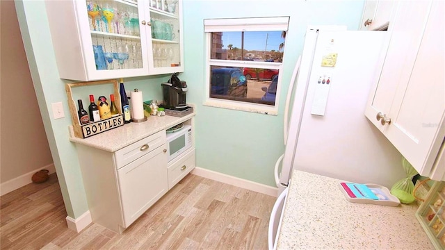 interior space with light stone countertops, white appliances, white cabinets, and light wood-type flooring