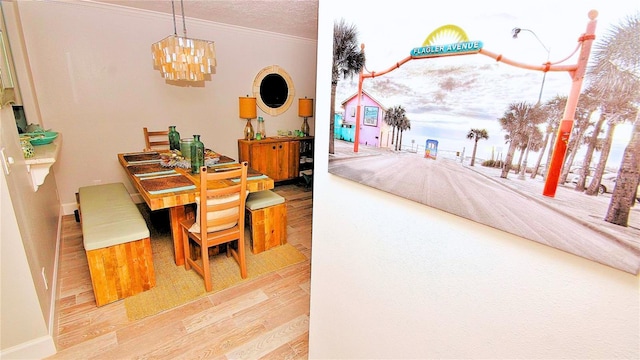 dining space with a textured ceiling, light hardwood / wood-style flooring, crown molding, and a notable chandelier