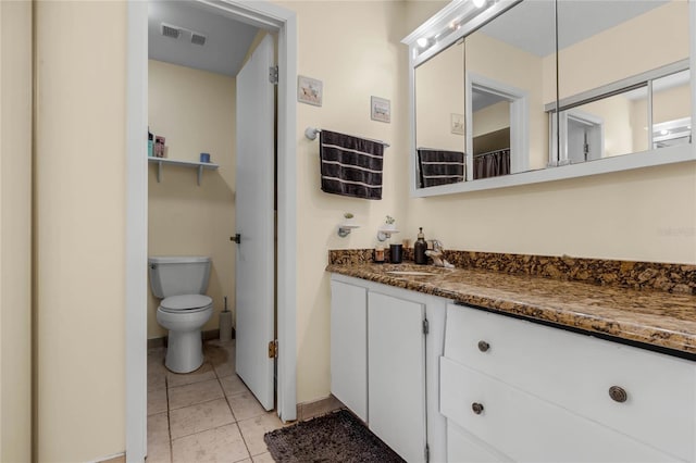 bathroom with toilet, vanity, and tile patterned floors