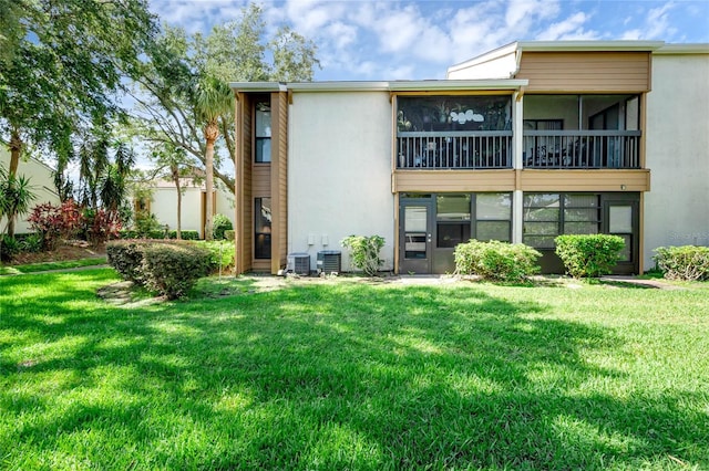 back of property with cooling unit, a yard, and a sunroom