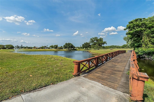 view of dock with a water view and a lawn