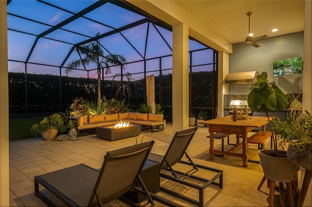 patio terrace at dusk featuring a lanai and an outdoor living space with a fire pit