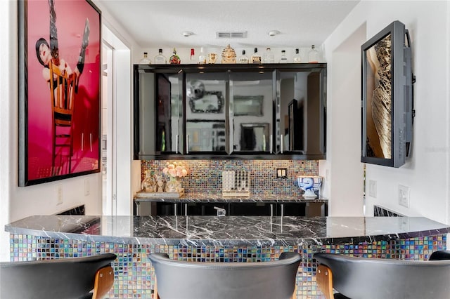 bar with backsplash and a textured ceiling