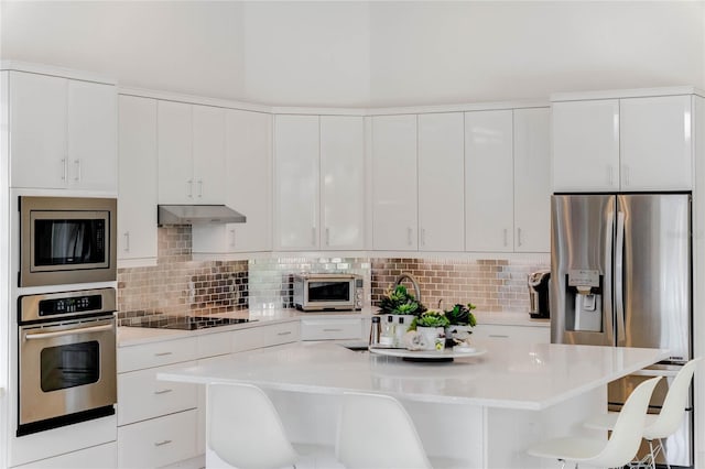 kitchen featuring a kitchen breakfast bar, white cabinetry, appliances with stainless steel finishes, and a center island