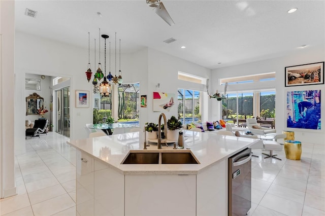 kitchen with sink, hanging light fixtures, and a kitchen island with sink