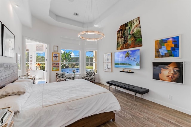 bedroom featuring wood-type flooring and a raised ceiling