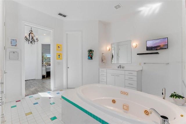 bathroom with tiled bath, vanity, and a chandelier